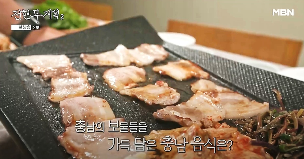 홍성 덕성식당의 냉동삼겹살이 불판 위에서 고사리, 김치와 함께 구워지고 있는 모습