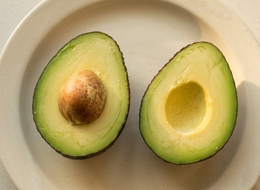 접시 위에 놓인 완벽하게 후숙된 아보카도 단면과 씨앗 제거 상태.