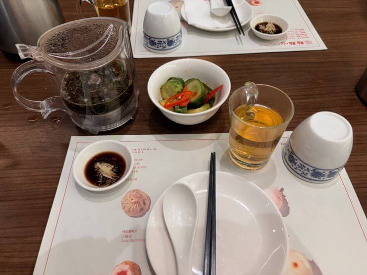 가운데 하얀 종이 가운데 하얀 접시가 있다. 접시 위에는 중국식 스푼이 왼쪽, 검은 젓가락이 오른쪽에 놓여있다.
접시를 기준으로 왼쪽이 작은 종지에 간장과 생강채가 있다.
접시기준 오른쪽에는 투명 컵에 금색 물(쟈스민차)이 담겨있고 그 옆에 흰색 컵이 있다.
접시 앞쪽에는 오이피클이 담겨져 있는 그릇이 보인다.
오이피클 왼쪽에는 투명한 차주전자가 있다.