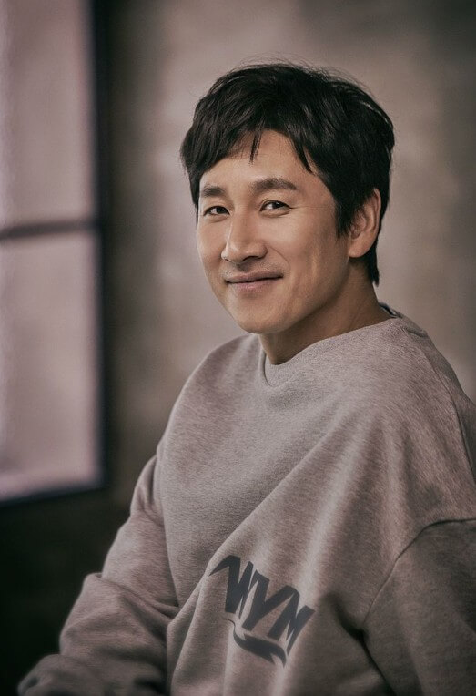 이선균의-화보-사진으로-회색-맨투맨-티를-입고-옅은-미소를-띄고-있다.