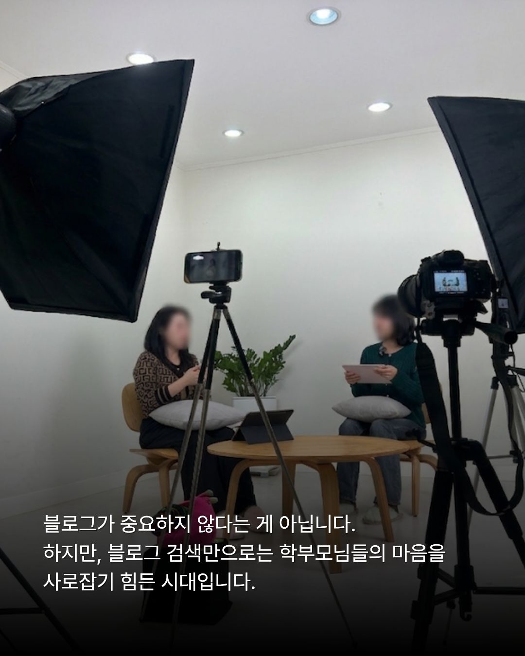 대형 소프트박스 조명과 카메라가 세팅된 스튜디오 현장에서 두 여성이 테이블을 두고 마주 앉아 소통하는 전경. 하단에는 '블로그가 중요하지 않다는 게 아닙니다. 하지만, 블로그 검색만으로는 학부모님들의 마음을 사로잡기 힘든 시대입니다.'라는 안내 자막이 포함되어 있습니다.