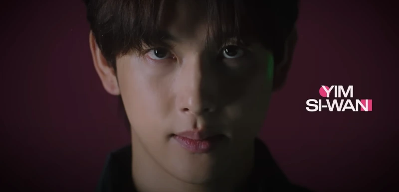 분홍색 배경에 가운데 전면을 무표정으로 응시하고 있는 오징어 게임 2에 등장하는 배우 임시완