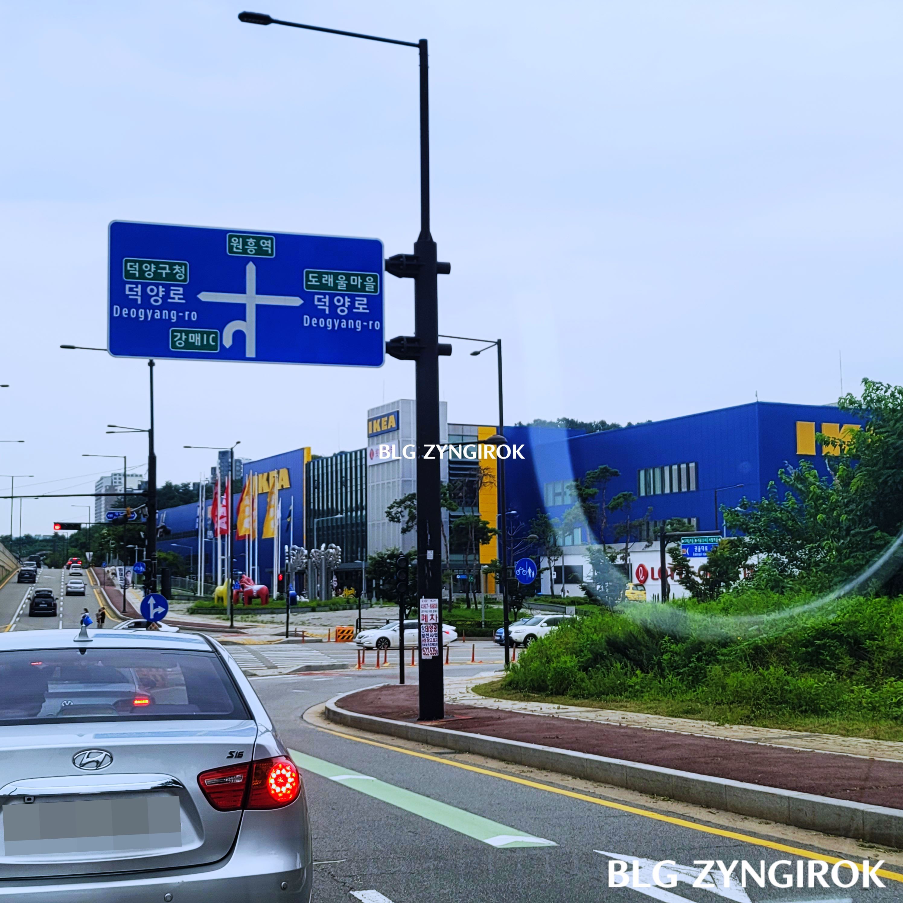 고속도로-인터체인지에서-내려와서-보이는-이케아의-모습이다.-파란색-벽의-이케아-건물이-길-대각선-건너편에-위치해있다.