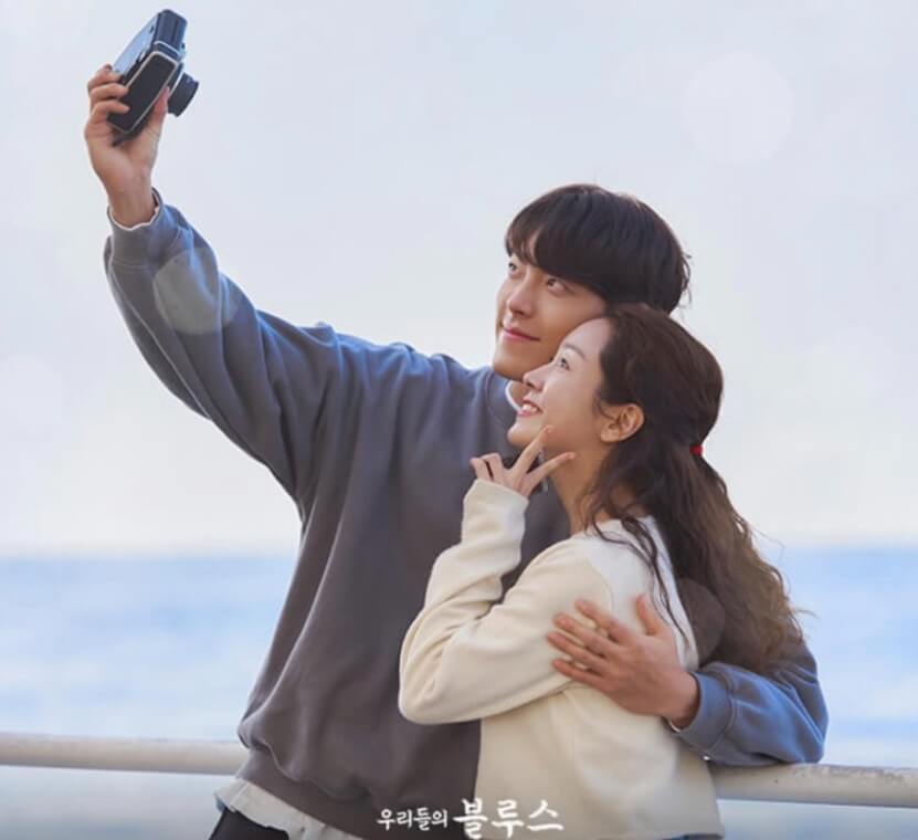 드라마 우리들의 블루스에서 김우빈과 한지만이 어깨 동무를 하고 폴라로이드 사진기로 다정하게 셀카를 찍는 장면