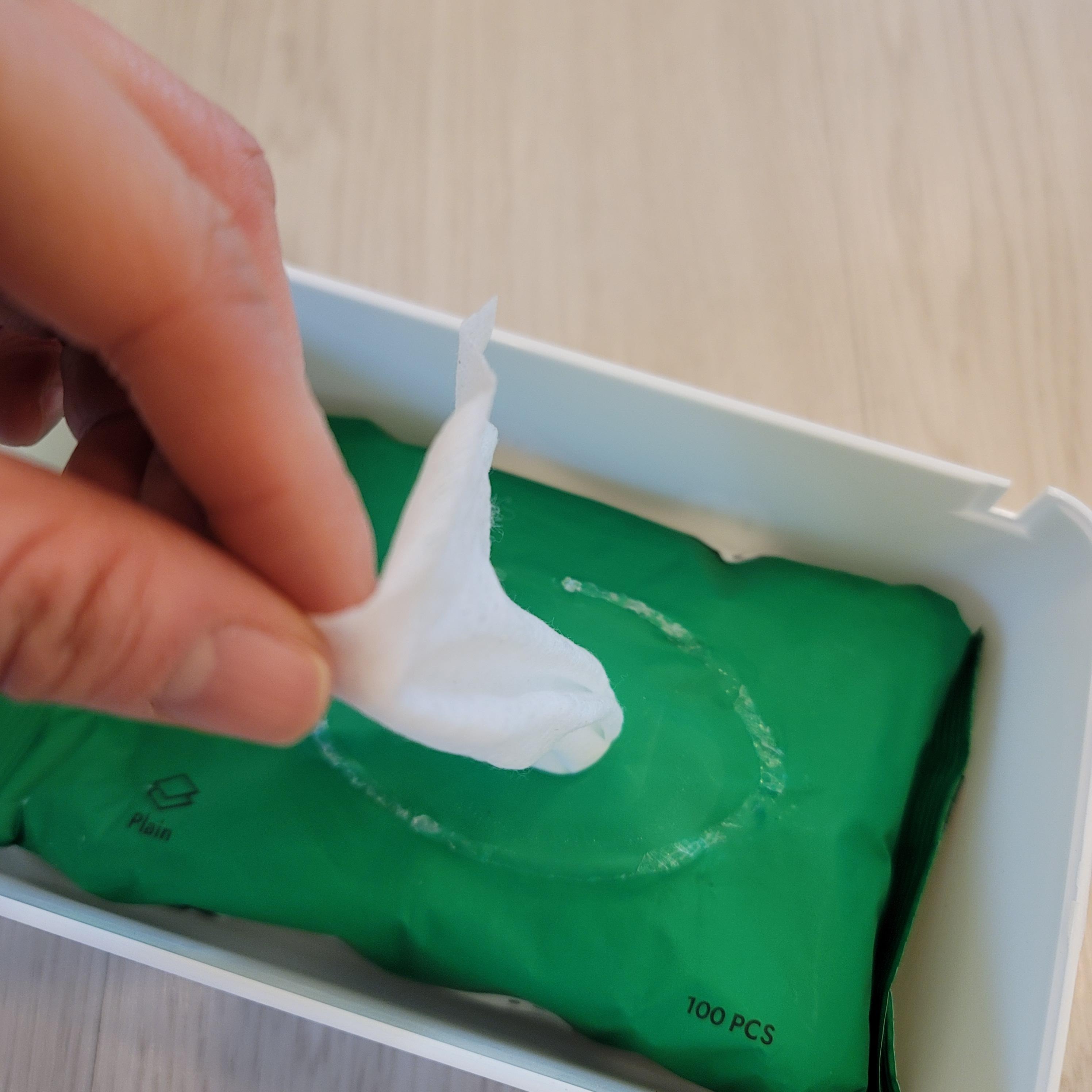 다이소 다용도 물티슈 케이스 안에 물티슈를 넣고 물티슈의 뚜껑을 제거 하고 물티슈를 살짝만 뽑아내고 있는 사진이다.