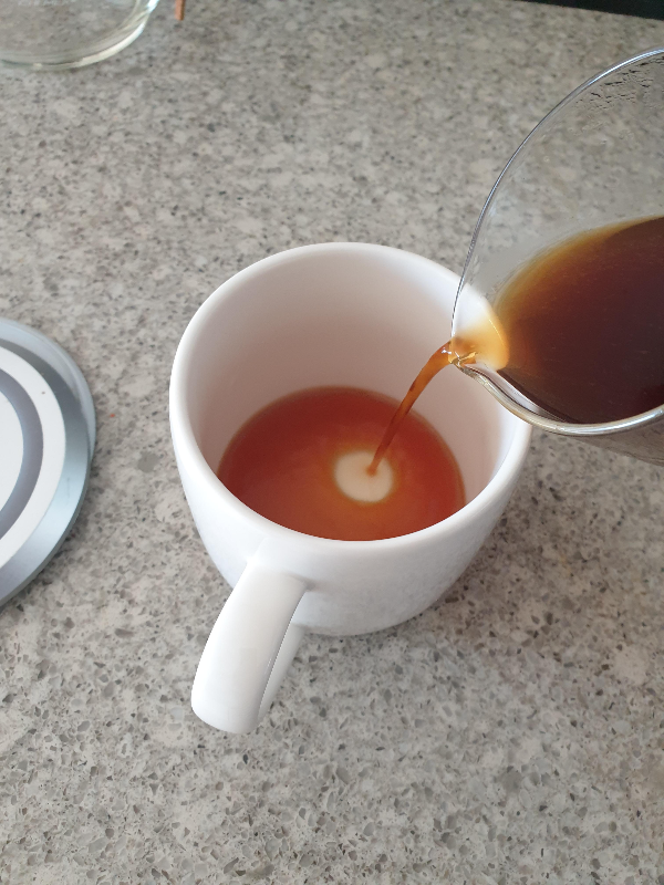 서버에 담긴 추출된 커피를 컵에 붓는 모습