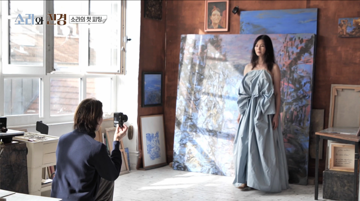 푸른빛 드레스를 입은 이소라가 그림 앞에 서서 촬영하는 방송 화면