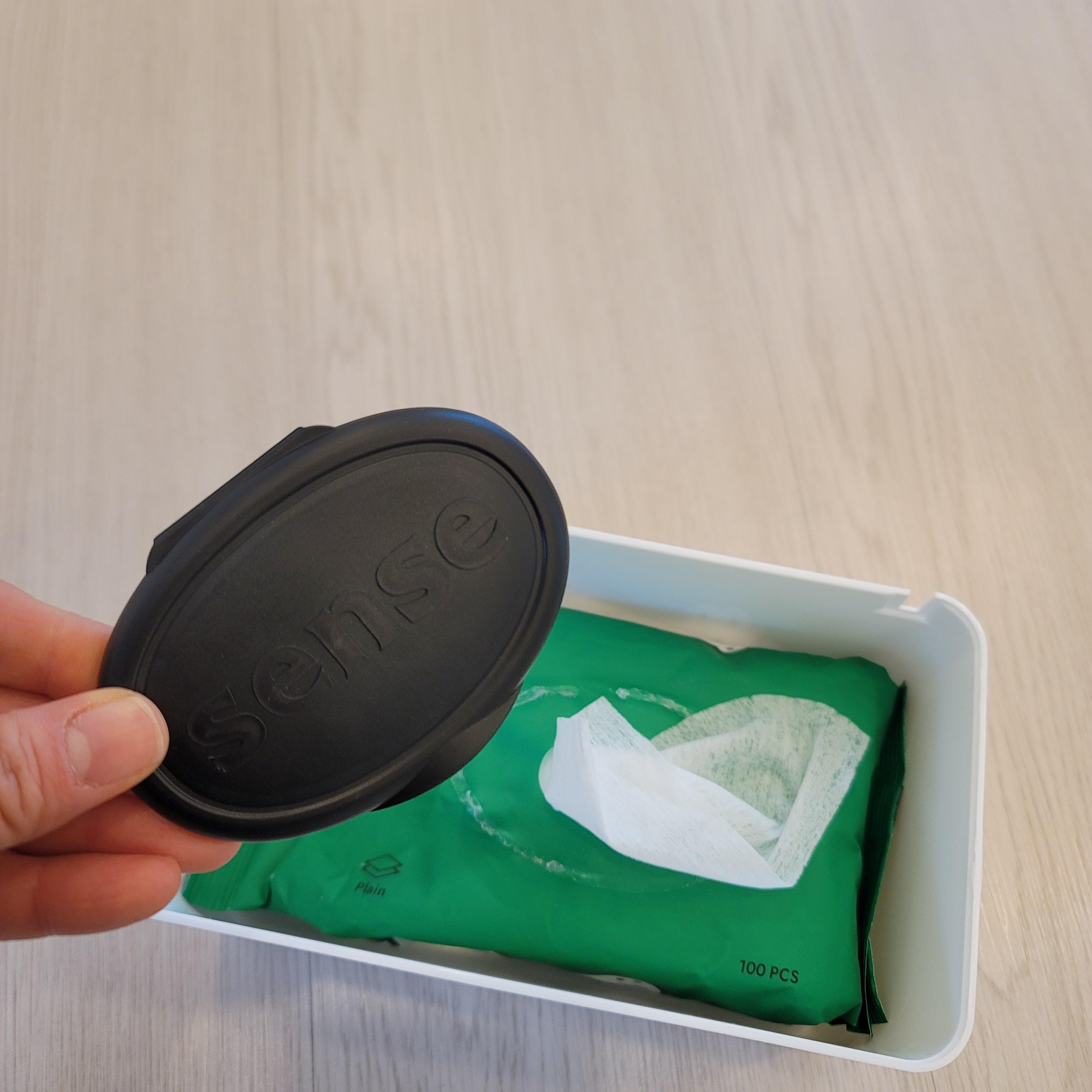 다이소 다용도 물티슈 케이스 안에 물티슈를 넣고 물티슈의 뚜껑을 제거 하고 있는 사진이다.