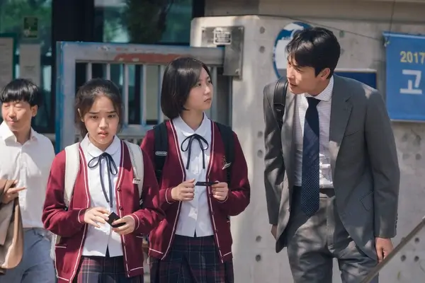변호사 순호가 증인 박지우의 학교 앞에 찾아가 말을 거는 모습