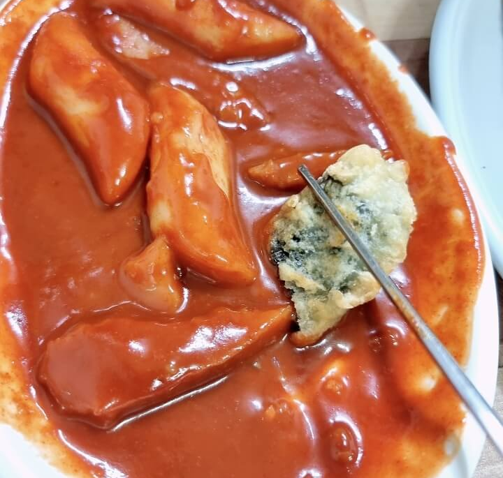 튀김을 떡볶이 소스에 찍어 먹고 있음