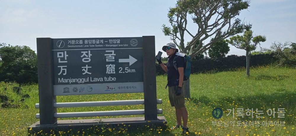 만장굴 2.5km 표지판 앞에 선 남성