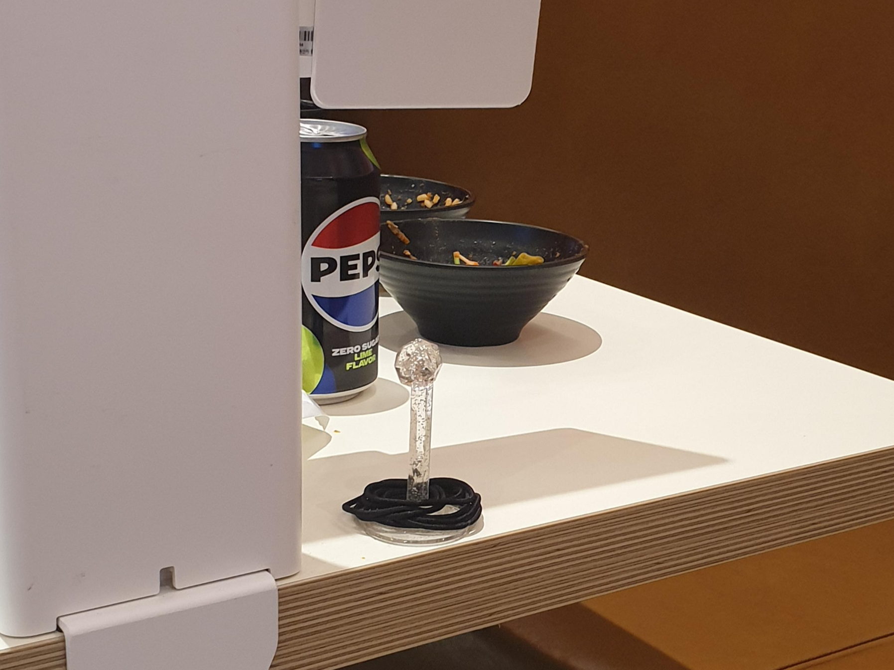 키오스크 뒷면에 작은 봉에 검정색 머리끈들이 놓여있다.