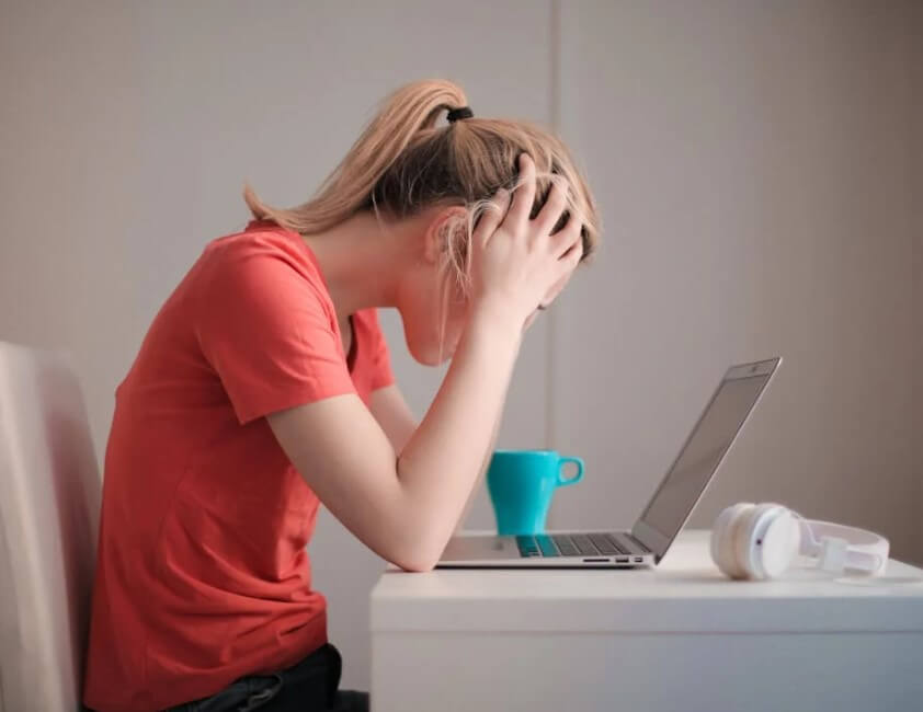 스트레스를 받은 여성이 머리를 감싸고 고개를 숙인 모습으로, 감정이 통제되지 않는 상황에서 나타나는 심리적 반응을 시각적으로 보여줍니다.