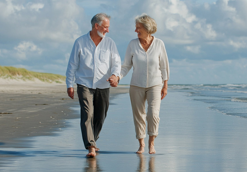 바닷가를 함께 걸으며 여유로운 노후를 즐기는 부부의 모습
