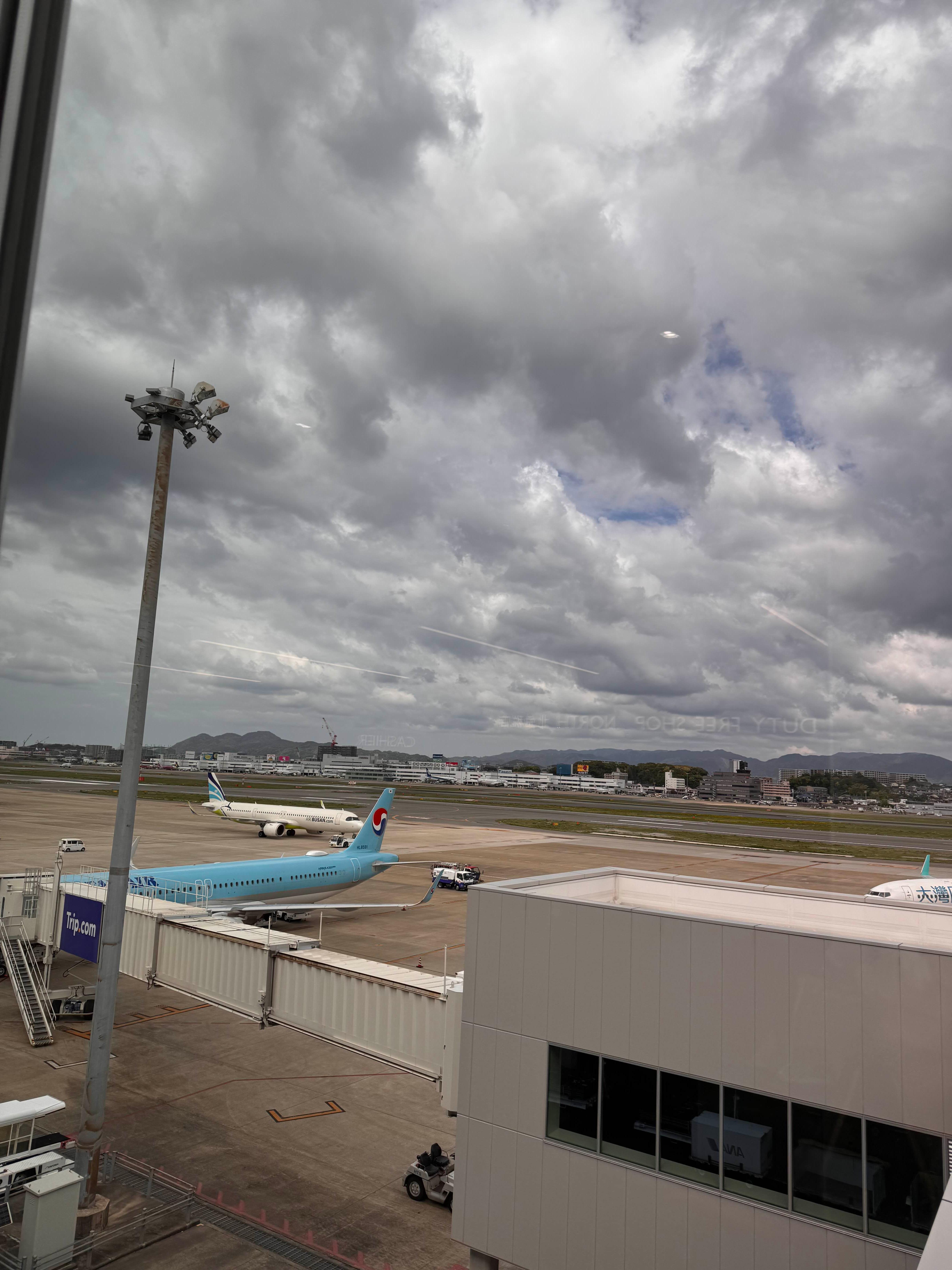 먹구름이 낀 흐린 하늘 아래 보이는 공항 활주로와 대기 중인 비행기