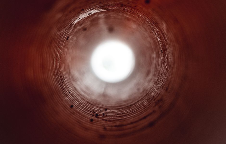 Surreal view inside a cylindrical tunnel with bright light at the end, symbolizing hope.