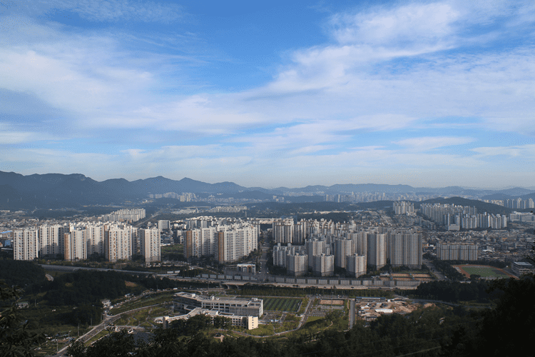 파란색-하늘의-초록색-산들-사이에-있는-흰색-아파트-여러-채