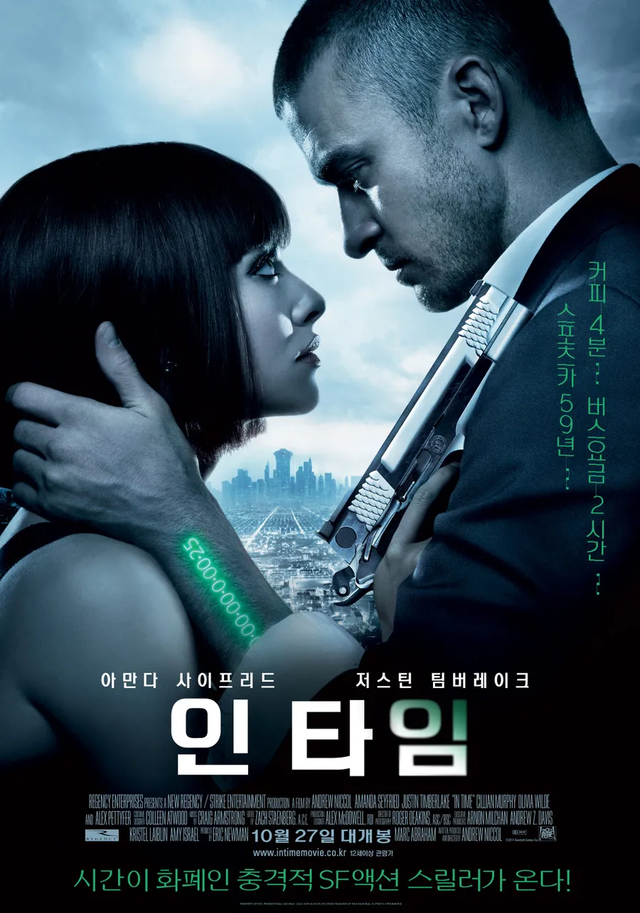 영화 포스터,"인 타임 (In Time)"
두 인물이 어둡고 미래적인 도시 배경 앞에서 서로를 강렬하게 응시하고 있다.