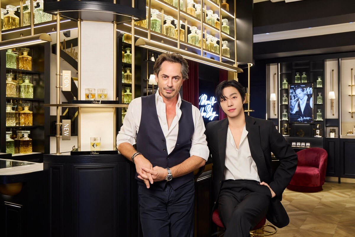 서울의 킬리안 파리 부티크에서 창립자 킬리안 헤네시와 배우 안효섭이 함께 포즈를 취하고 있다. 고급스러운 향수병들이 진열된 배경 속, 킬리안 헤네시는 셔츠와 조끼 차림으로 서 있고, 안효섭은 블랙 수트와 화이트 셔츠를 입고 앉아 세련된 분위기를 자아낸다