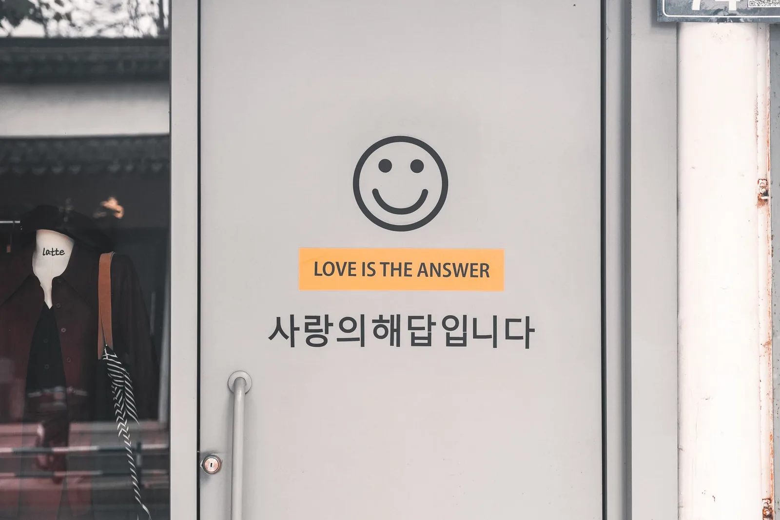 회색 문에 미소 짓는 얼굴과 영어 및 한국어로 된 '사랑은 답이다' 문구가 있습니다.