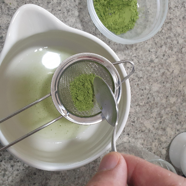 물이 담긴 다완에 말차가루를 체에 걸르는 중