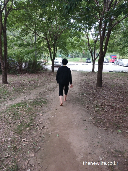 광나루 한강공원의 서울 맨발 걷기 좋은 숲길에서 주차장 방향으로 맨발 걷기하는 여성