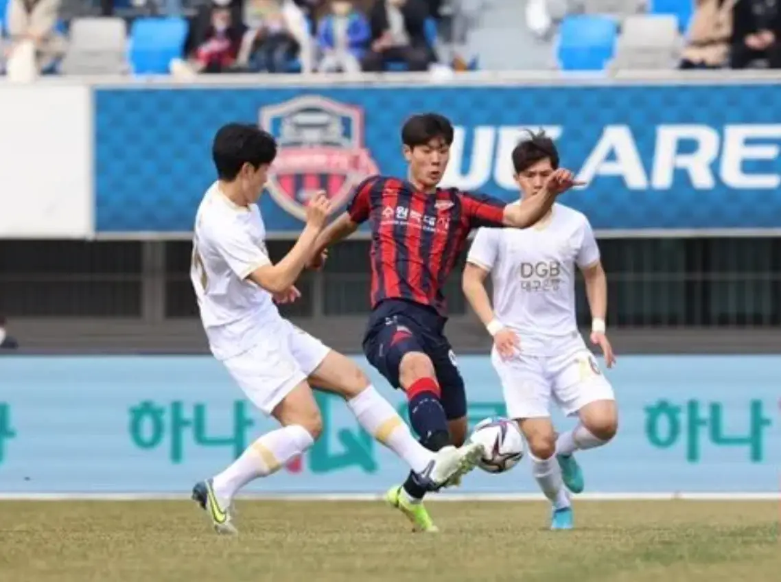 이영준- 붉고 파란 세로줄무늬 유니폼을 입은 이영준이 공을 차고 주변에 흰옷을 입은 두선수가 방해하는 모습