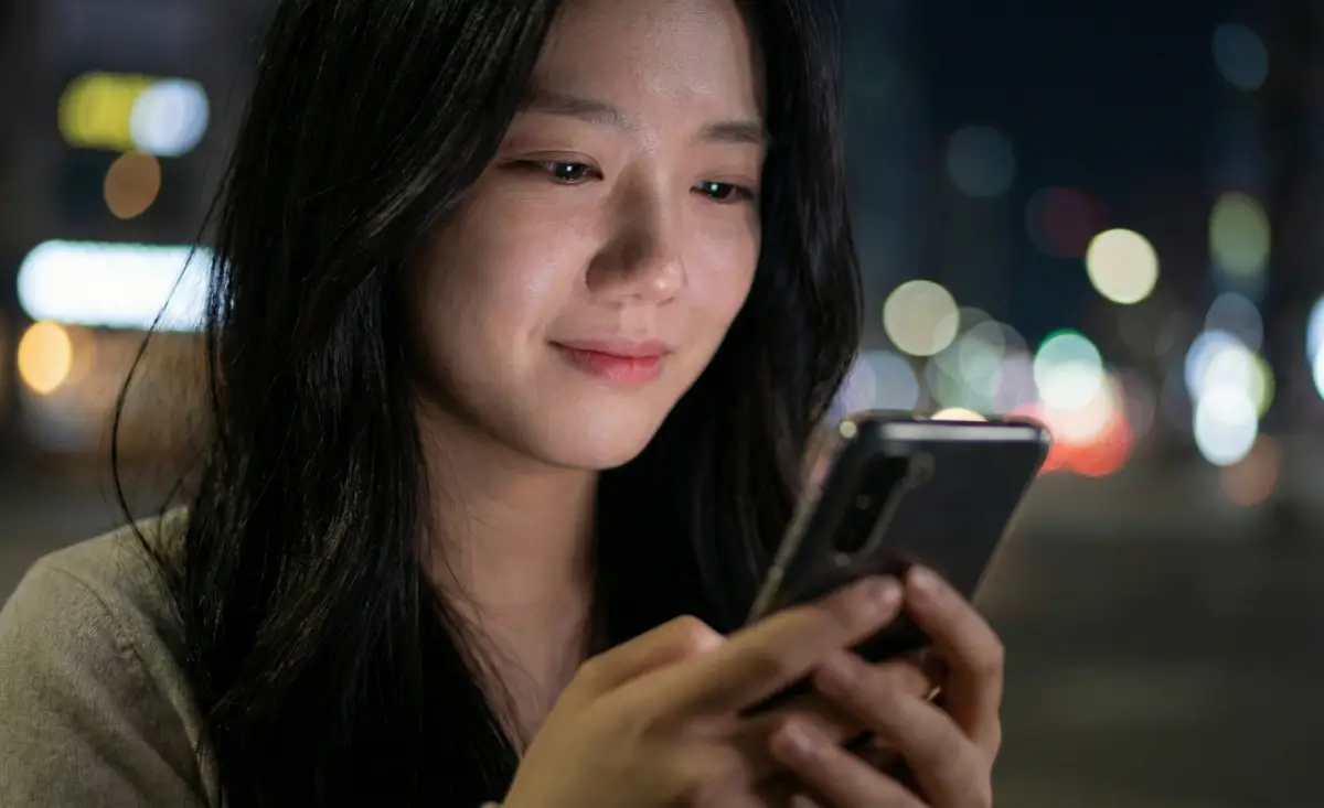 밤거리에서 핸드폰을 보며 이별 메시지를 보내려는 여성의 손 클로즈업