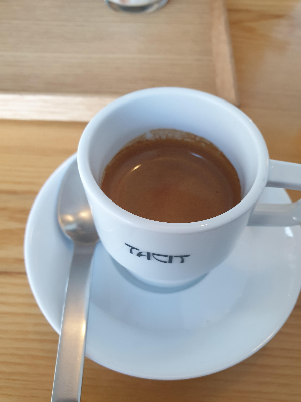 테이블 위에 에스프레소가 담긴 잔과 스푼이 놓여있다.