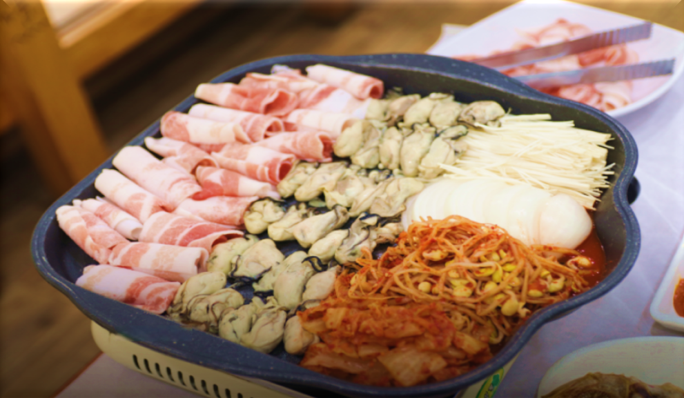 대패삼겹살,-데친-굴,-김치와-양파,-팽이버섯이-올려진-굴삼합구이