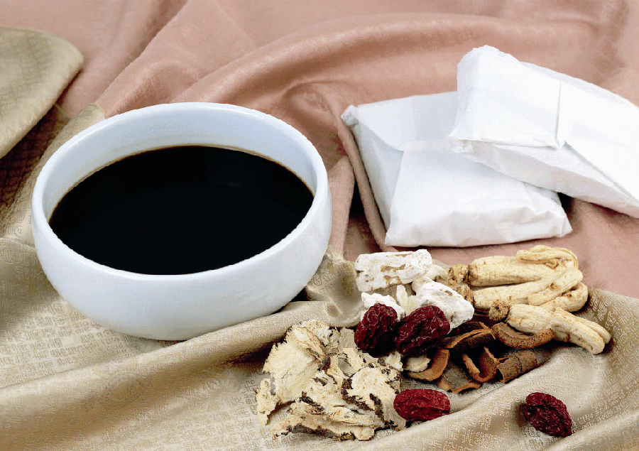 야생에서 채취를 한 한약재를 넣고 끓인 한약을 가득 담은 동그랗고 하얀 그릇과 그 옆에 한약을 담은 첩약과 인삼, 대추, 당귀, 산약, 계피 등을 놓아두고 찍은 사진