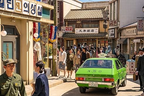 1970년대 분위기의 복고풍 거리에서 사람들이 걷고 있고&#44; 개인 택시가 거리 한가운데 서 있는 모습