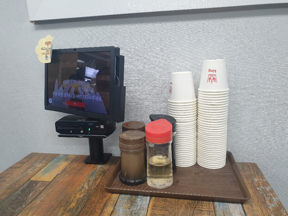 태블릿과 컵 그리고 각종 양념들이 올려져 있는 테이블