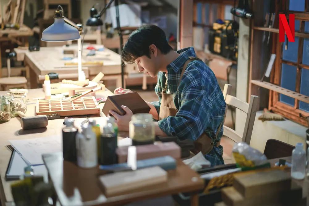 어느 공방에서 작업복을 입고 앉아서 나무 상자를 만들고 있는 드라마 너의 시간 속으로의 구연준 캐릭터