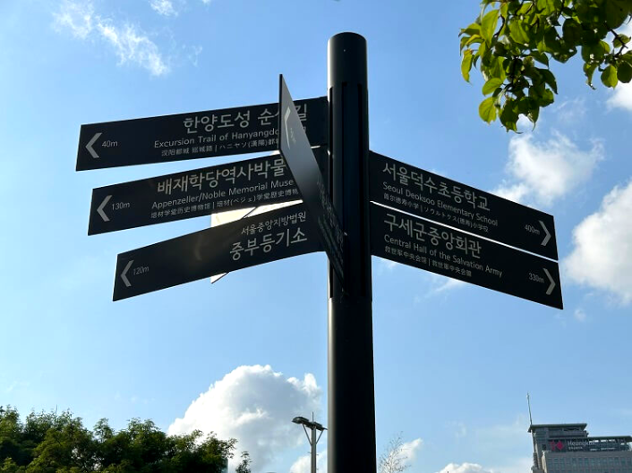 회색-바탕에-흰색-글씨가-인쇄된-이정표를-찍은-사진