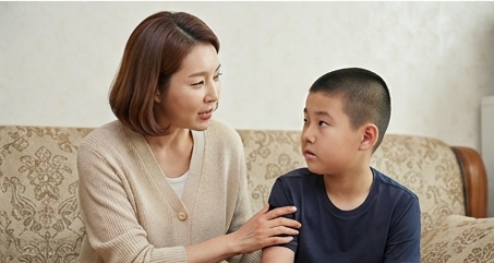 엄마가 아들 옆에 앉아 조용히 이야기 나누는 모습