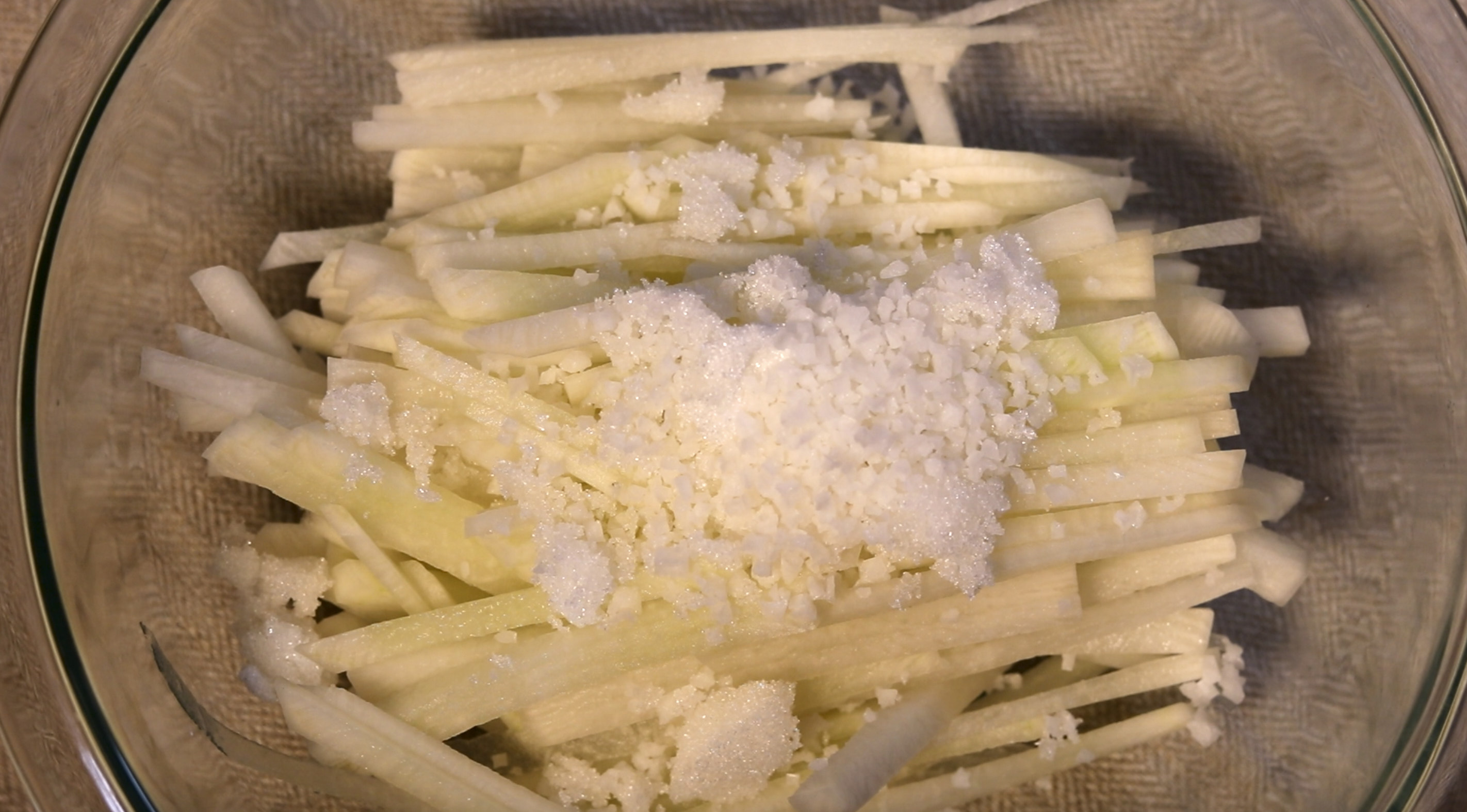 채 썬 무를 볼에 담고 소금 1스푼, 설탕 1스푼을 담는다