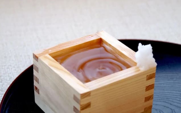 나무 안에 투명한 액체가 들어가 있고 나무의 모서리 위에 소금이 조금 올라가 있다.