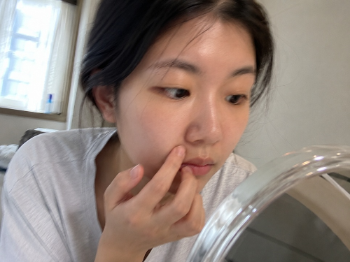 20대 여성이 거울을 보며 팔자주름을 걱정하는 모습