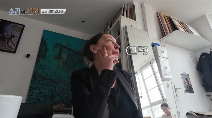 검은 옷을 입은 오디션 관계자가 실내에서 고개를 돌린 방송 화면