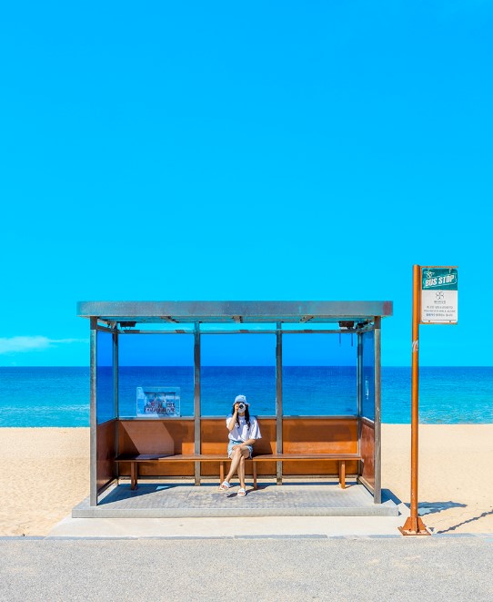 버스정류장 안에 사람이 앉아있다.