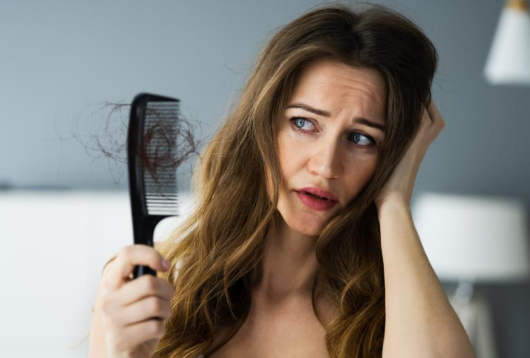머리가 긴 여성이 빗질을 했는데 머리카락이 많이 빠져 속상해하고 있다.