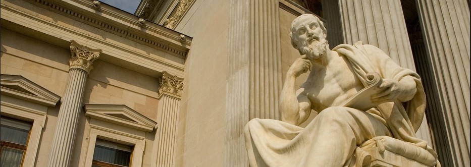 그리스 신전처럼 생긴 건물 앞에 생각에 잠긴 철학자 처럼 보이는 남성의 동상이 있는 사진