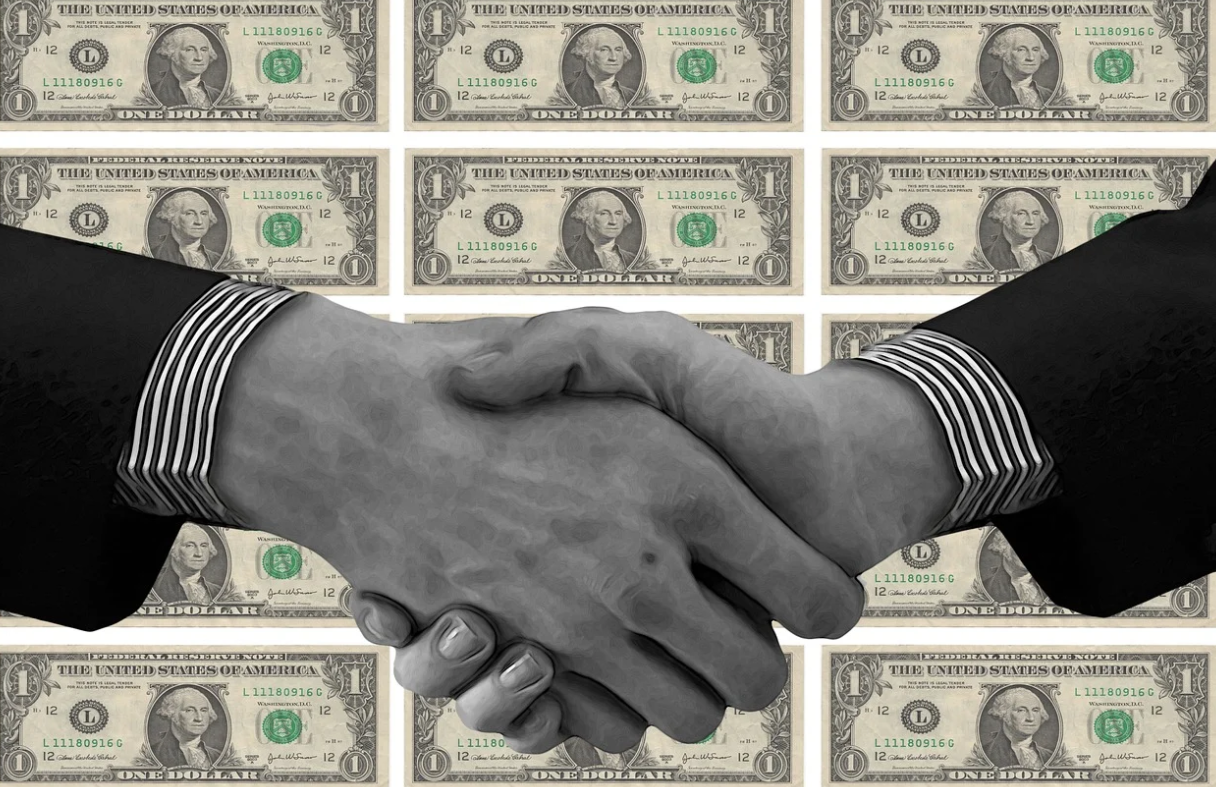 1달러 배경 앞에 악수하는 손