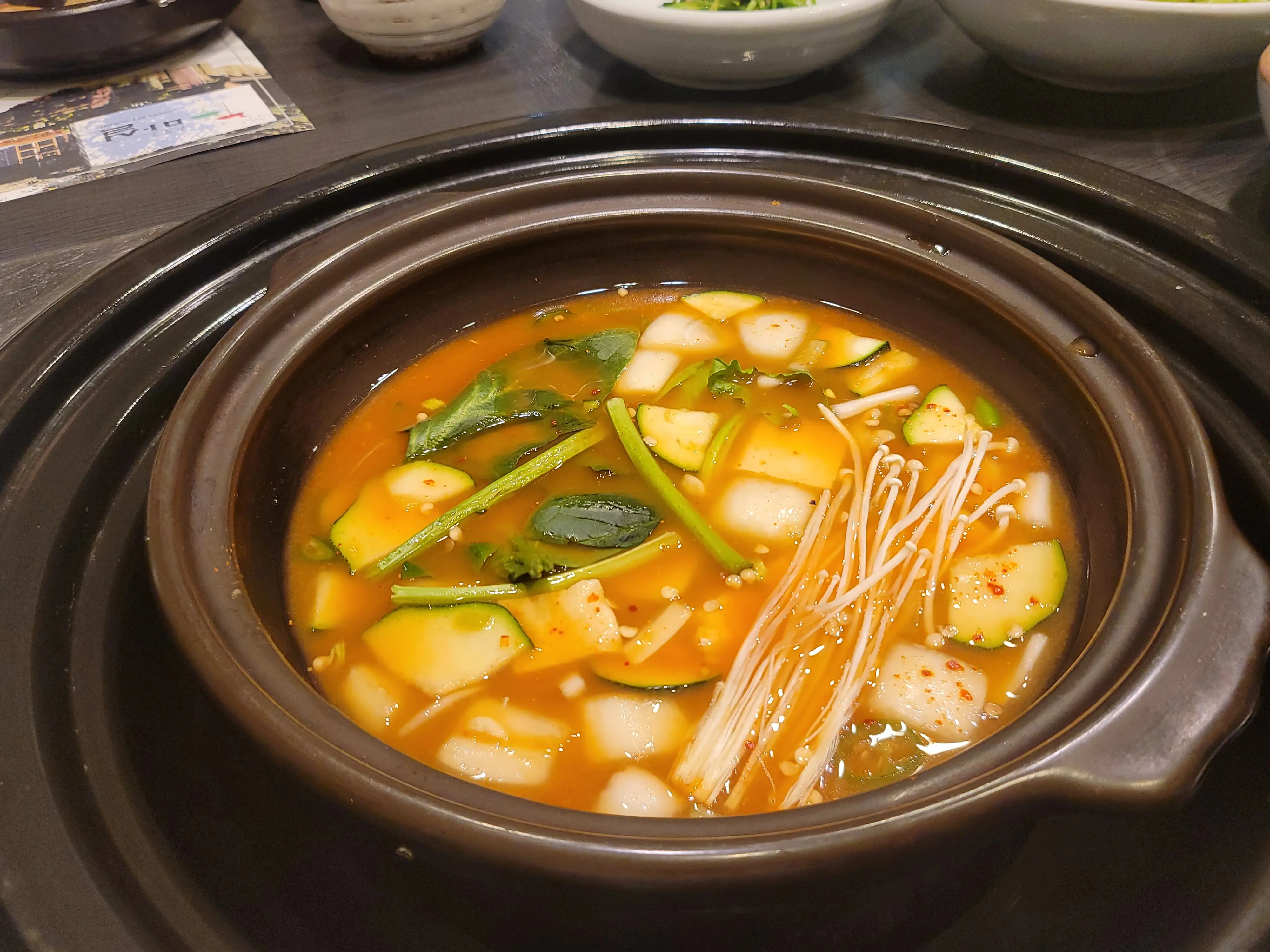 된장찌개. 사기냄비에 담겨져 나오며 가스레인지에 올려서 테이블에서 끓여먹는다. 애호박&#44; 양파&#44; 두부&#44; 팽이버섯등이 들어가있다.