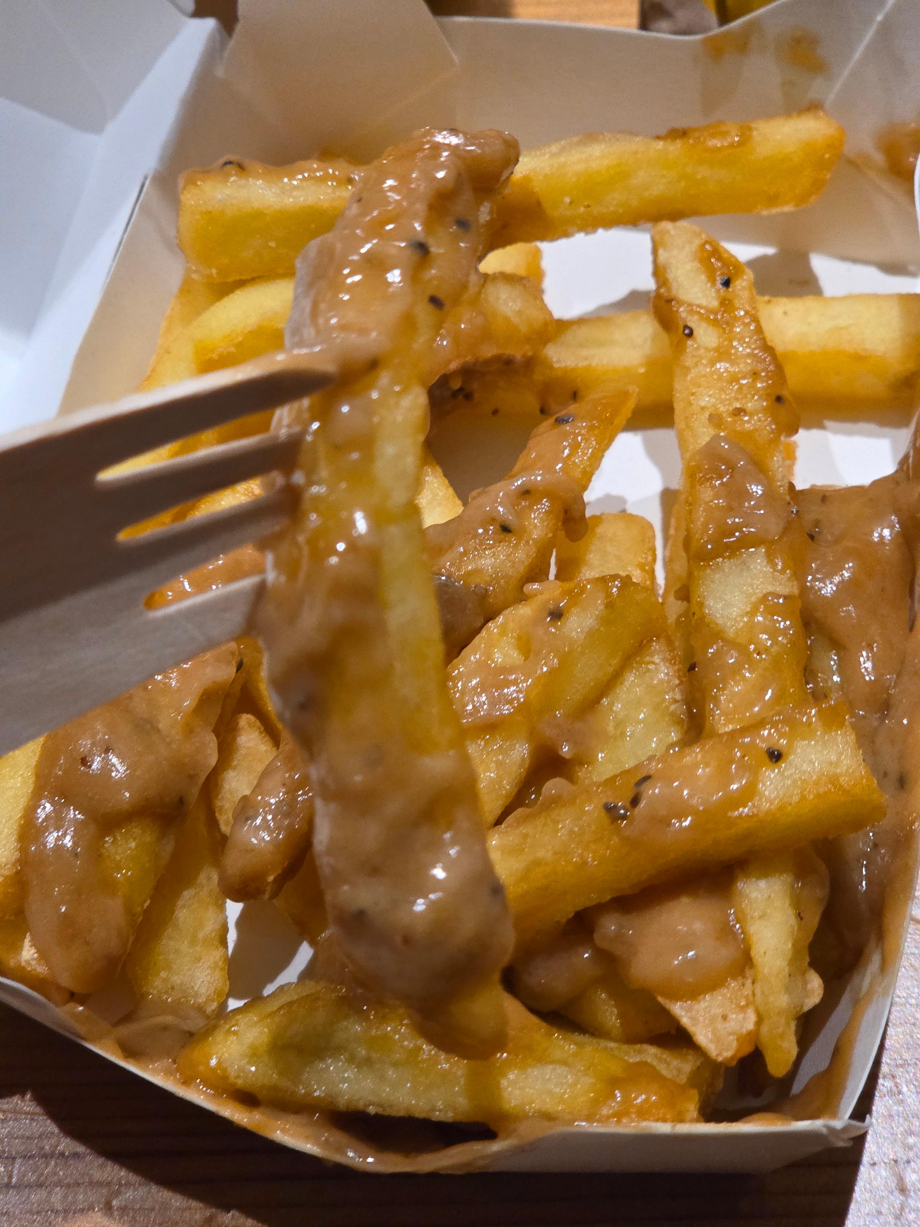 딥 트러플 프라이 단품을 가까이 찍은 사진으로 감자튀김 위에 트러플 소스가 넉넉히 뿌려진 모습