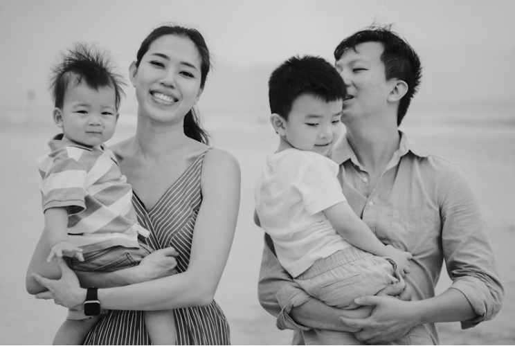 두 자녀를 둔 젊은 부부가 해변에서 웃으며 가족 시간을 보내는 모습