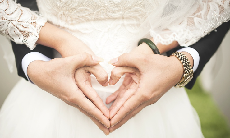 신랑 신부가 서로 손을 잡고 하트를 그리고 있는 사진