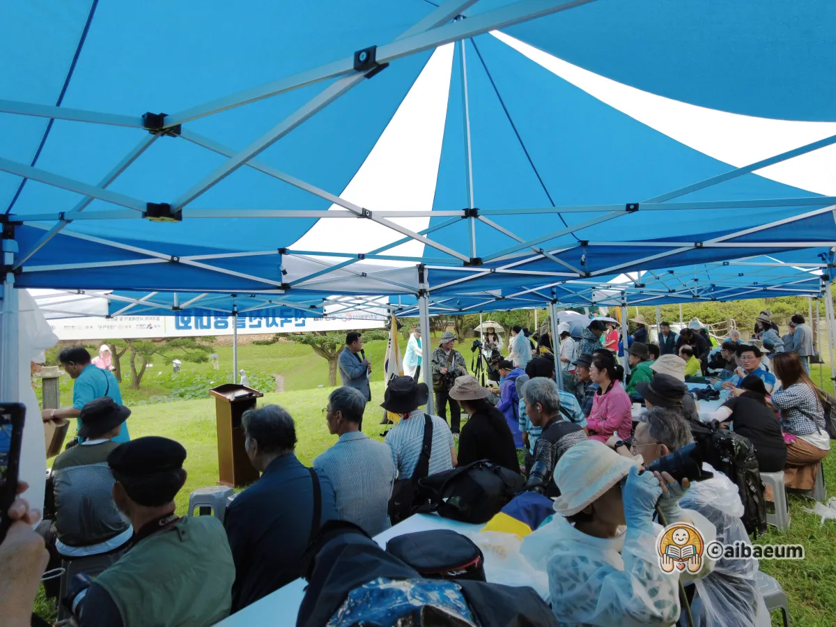 비가-와도-행사는-진행중-많은-사람들이-사회자의-이야기를-듣고있음