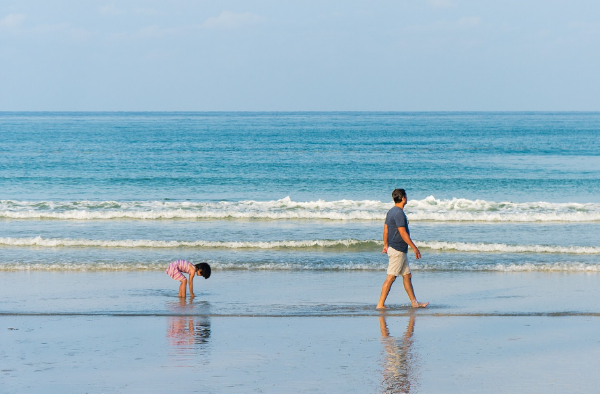 해변가를 걷고 있는 아빠와 딸의 모습